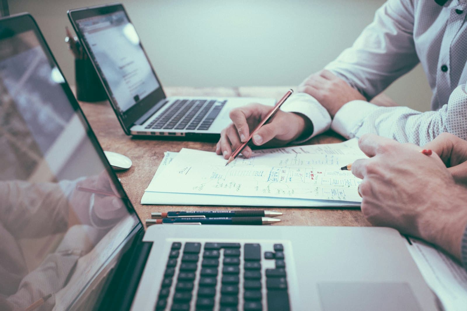 A desk with laptops and printed financial records under review.