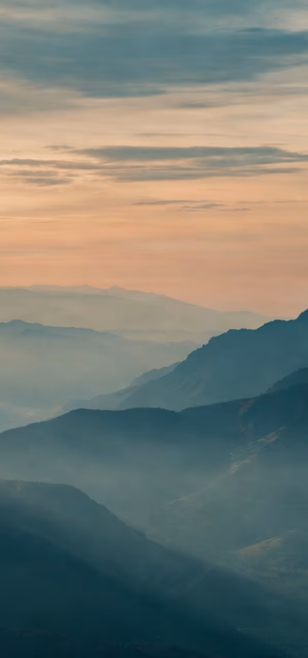 Mountain ridges fading toward a dawn horizon.